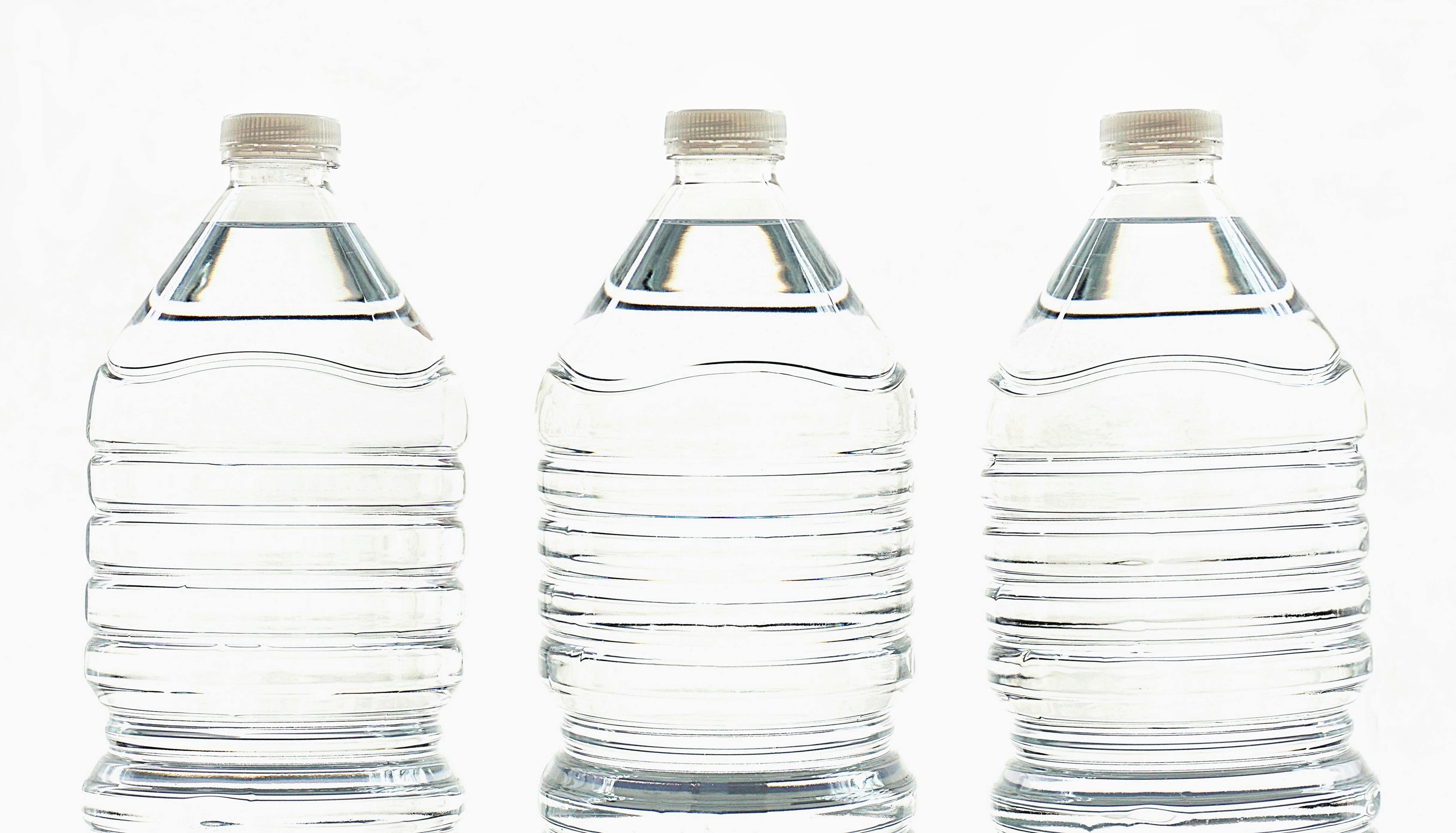 Three clear plastic bottles filled with water, standing side by side.