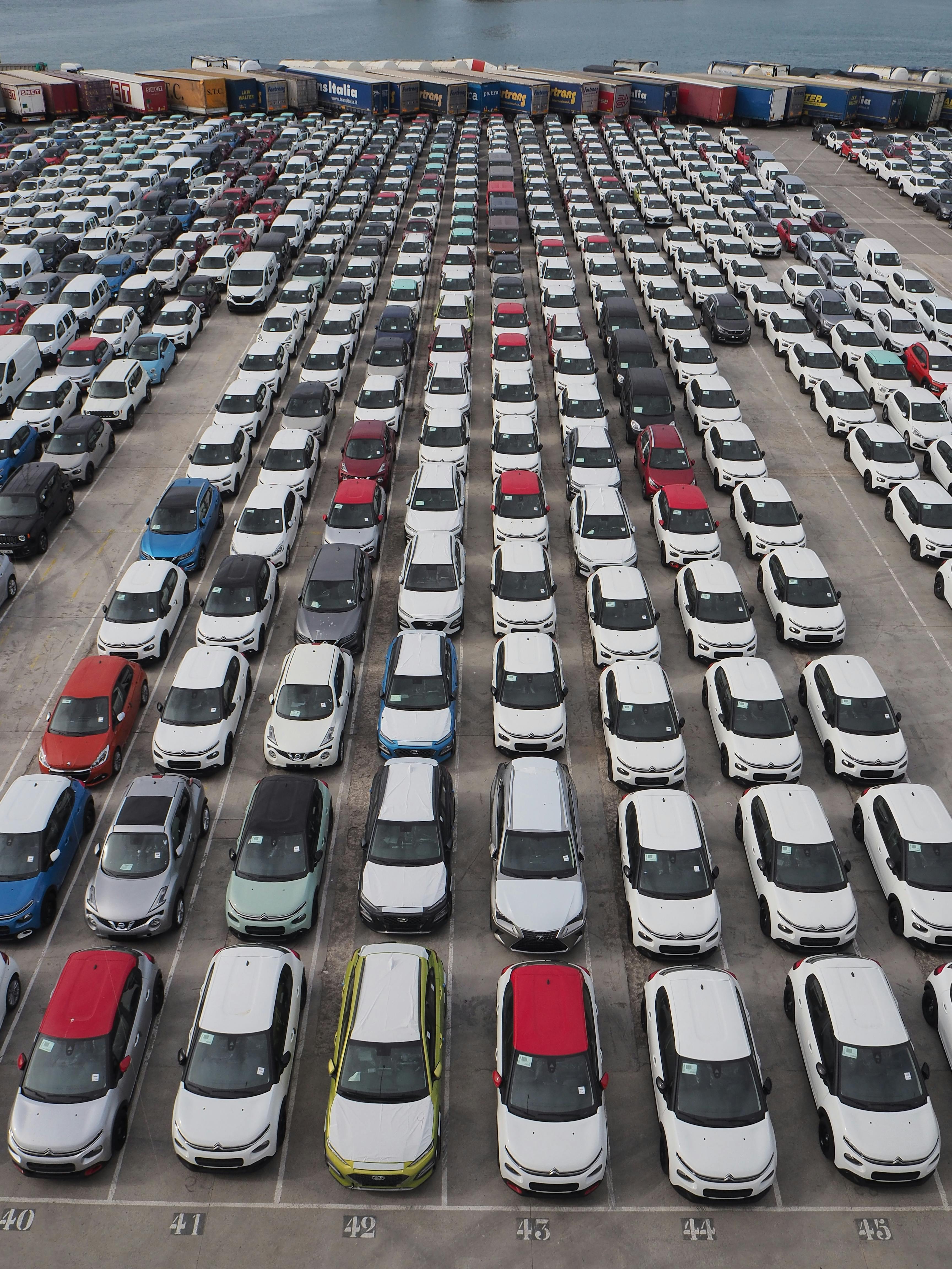 Top-down view of a large parking lot with rows of cars in Barcelona's port area.